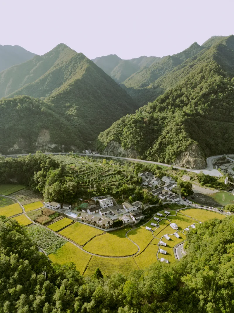 Aerial view of the compound nestled between rice paddies and winding roads in a mountain valley