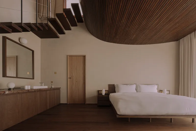 Bedroom interior with curved timber slat ceiling and floating staircase treads overhead