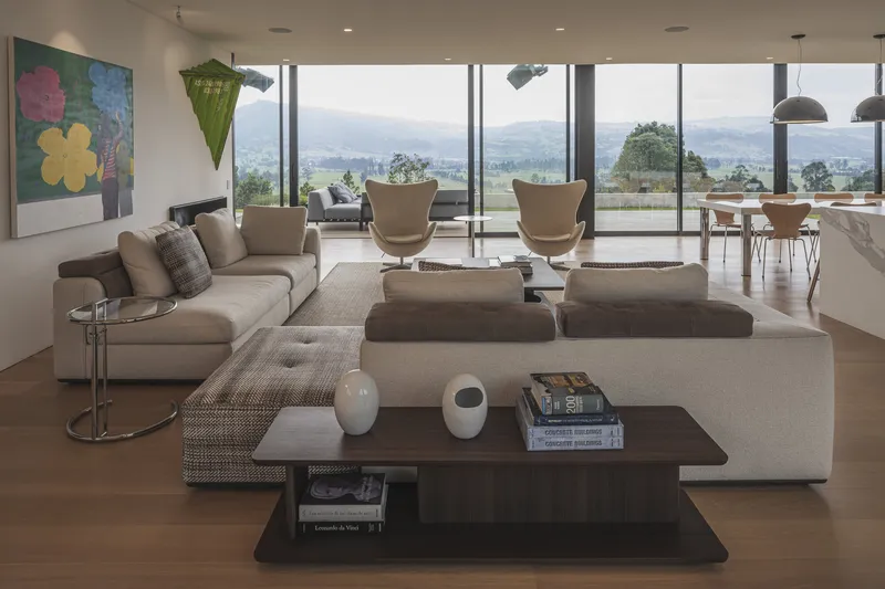 Open-plan living room with floor-to-ceiling glass overlooking distant hills and valleys