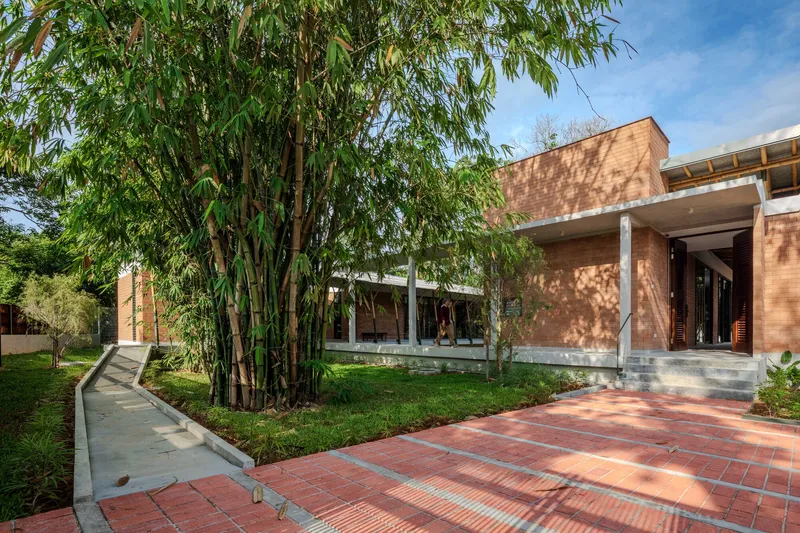 Red brick facade with overhanging roof beside bamboo grove and patterned tile courtyard