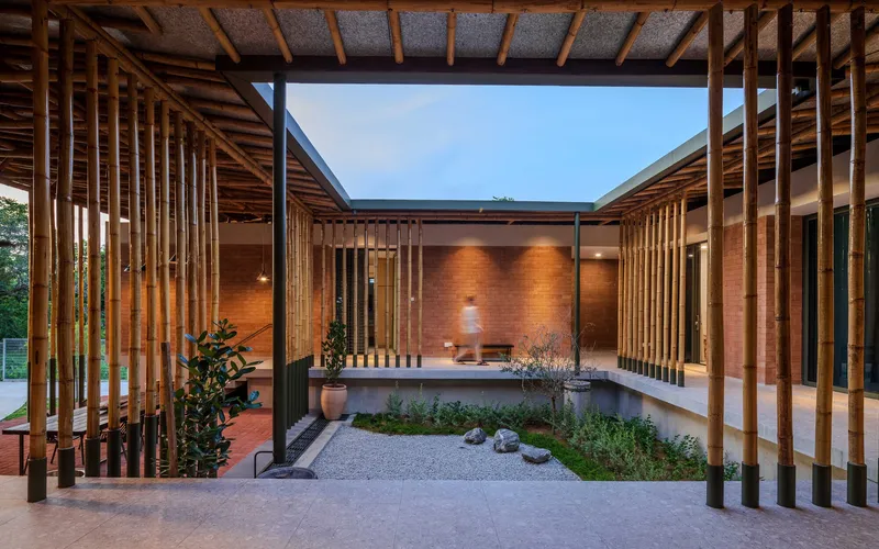 Courtyard with vertical timber screens surrounding reflecting pool and brick wall at twilight