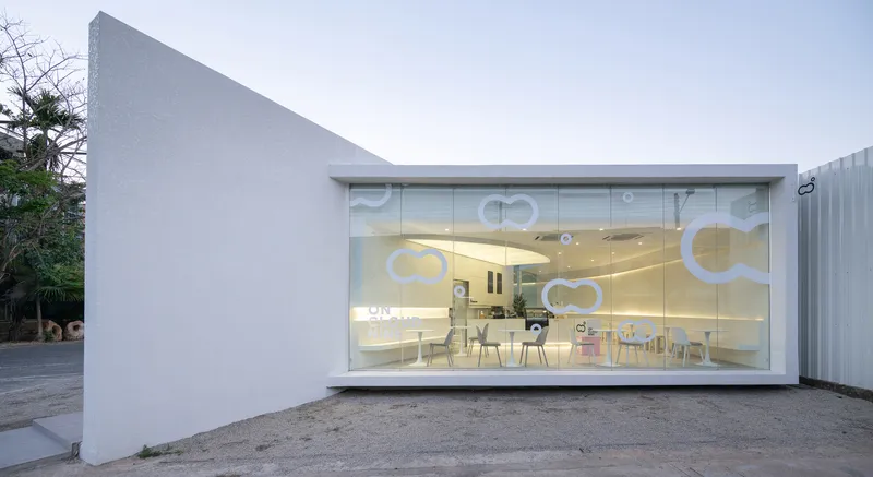 Transparent glass storefront with logo graphics revealing interior seating and warm ceiling light at twilight