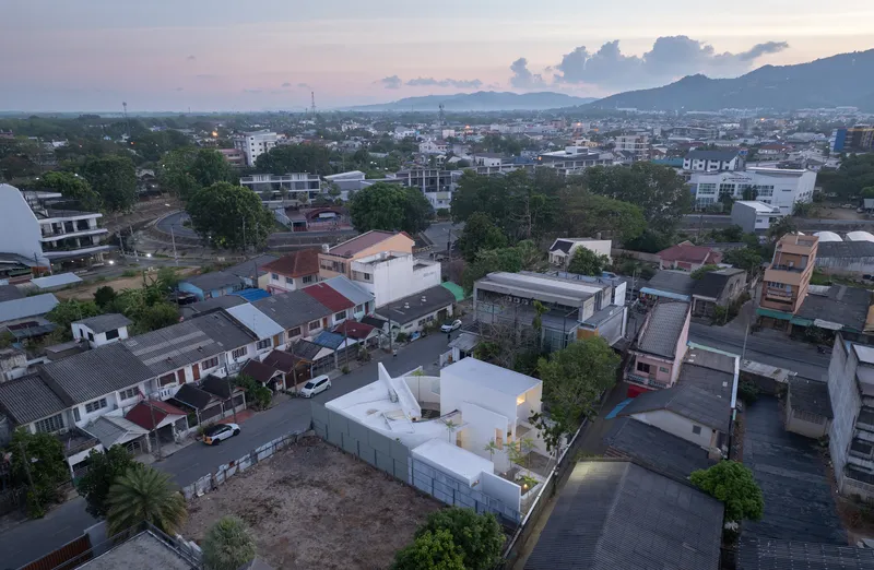 Aerial view of the white angular volumes set within a dense residential neighborhood at dusk