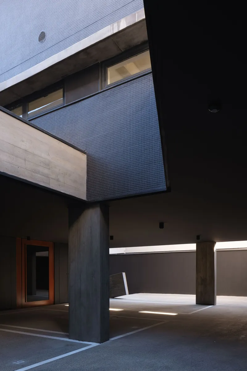 Interior courtyard with concrete columns, exposed timber beams and slots of natural light through horizontal openings