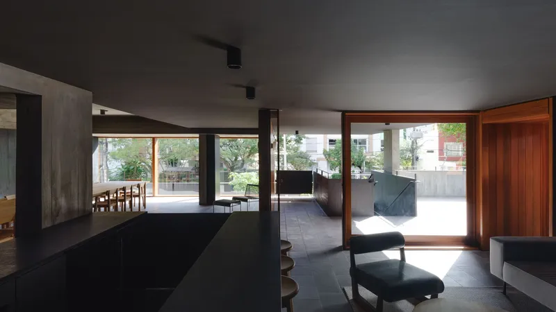 Open-plan living space with black island and timber-framed glazing opening to the terrace in daylight