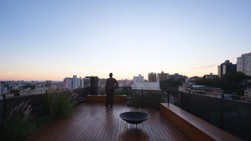 Rooftop terrace with timber decking and planted grasses overlooking the cityscape at dusk