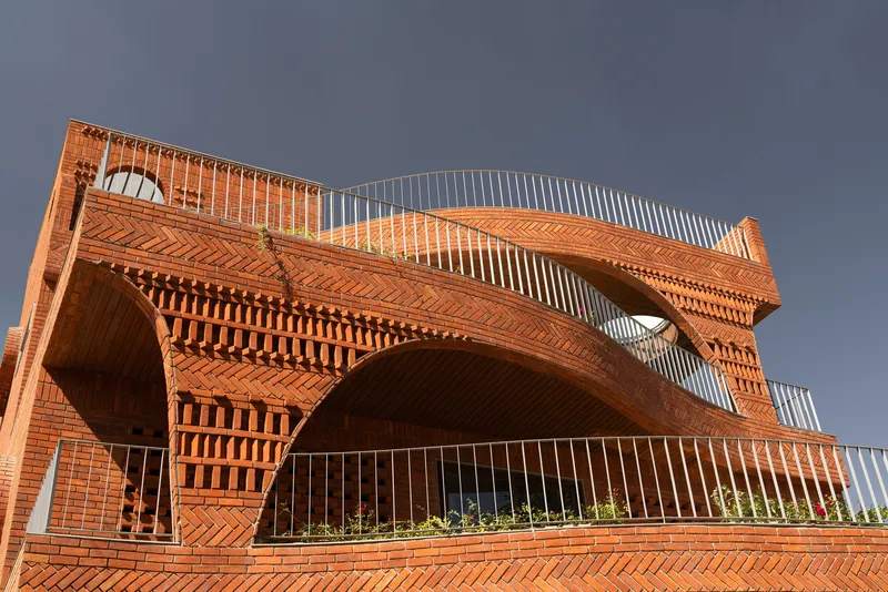 Cantilevered brick arches and diagonal brickwork patterns spanning the upper facade under dark sky