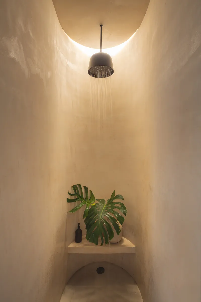 Illuminated shower alcove with water flowing from a perforated ceiling fixture at night