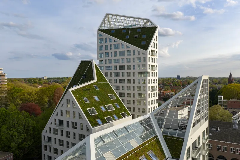 Aerial view of the clustered towers with planted and glazed gable roofs under partly cloudy skies