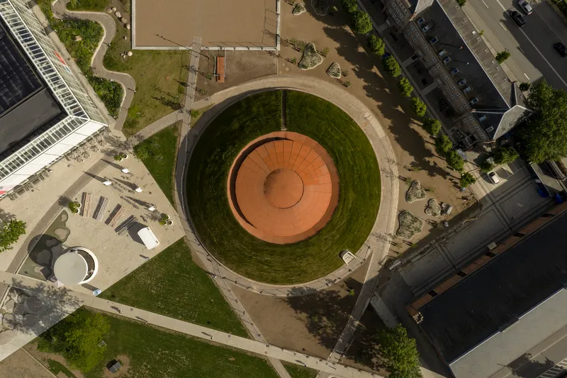 Aerial view of the circular rooftop plaza with concentric rings of terracotta paving and grassy slopes