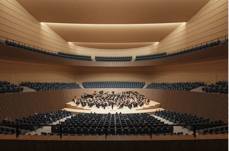 Concert hall interior with terraced timber seating and orchestra on stage during a performance
