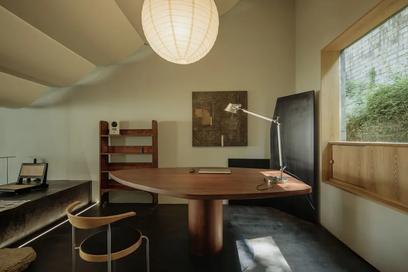 Office space with round timber table and paper lantern beside a glass brick window