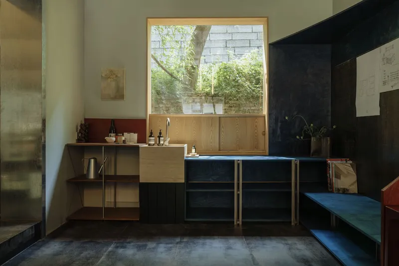 Kitchen counter and window overlooking courtyard with concrete block retaining wall and greenery