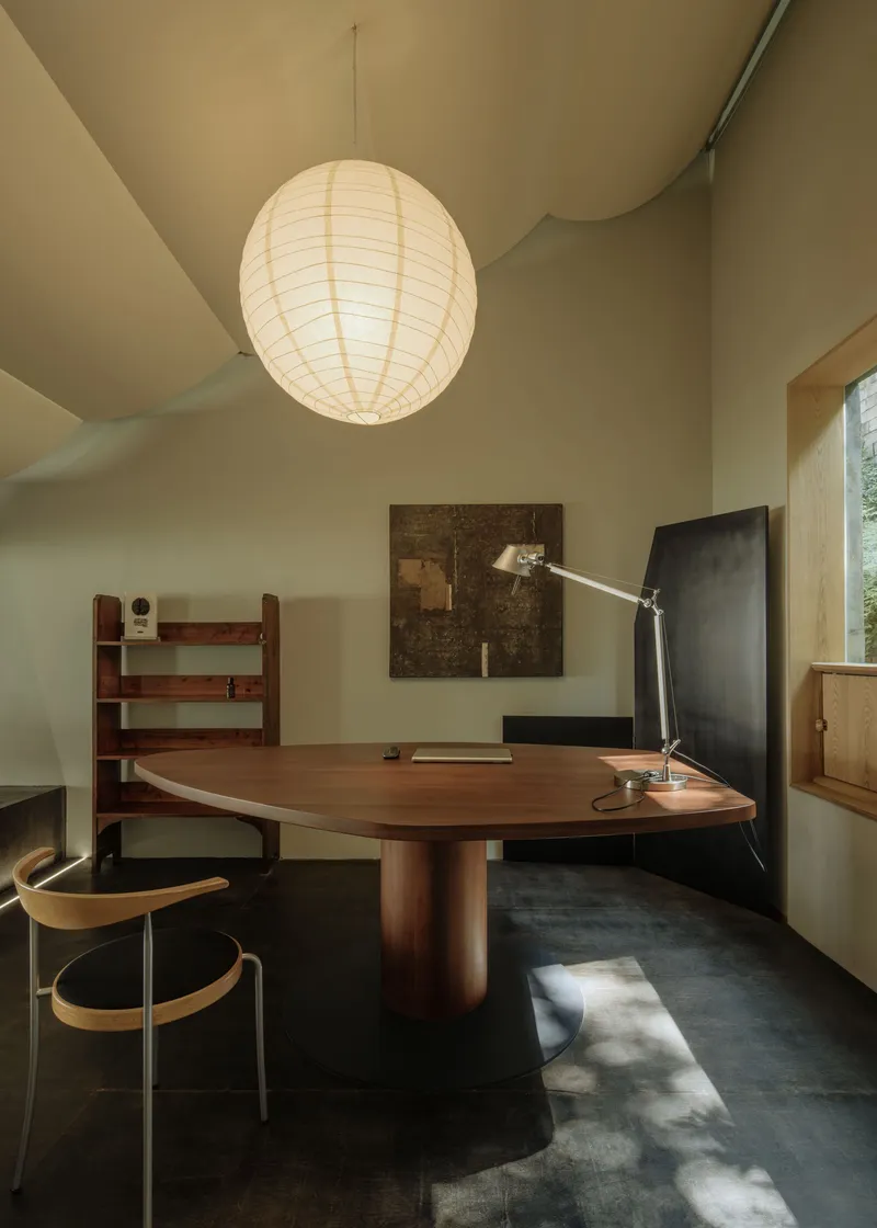 Workspace showing walnut desk with articulated lamp and paper globe pendant in afternoon light