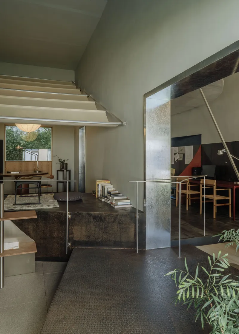 Double-height interior with floating staircase and glass balustrade connecting split levels
