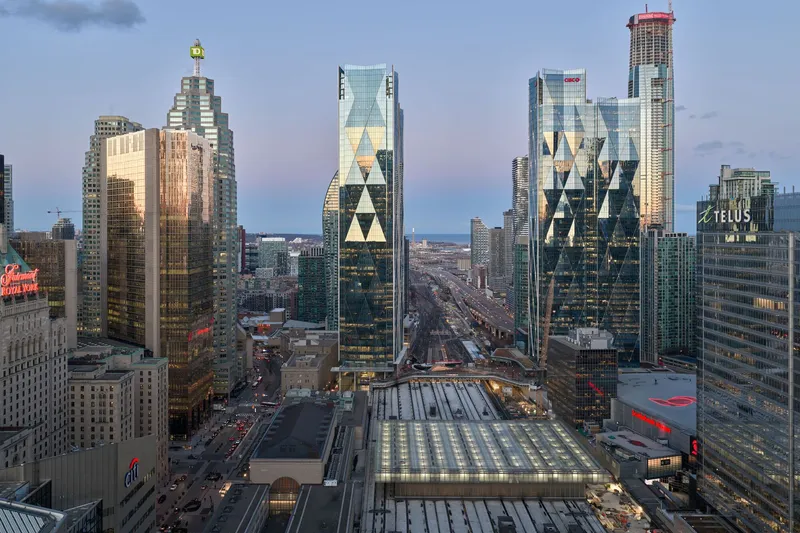 Elevated dusk view of the towers and rail shed with illuminated glass roofs and surrounding cityscape