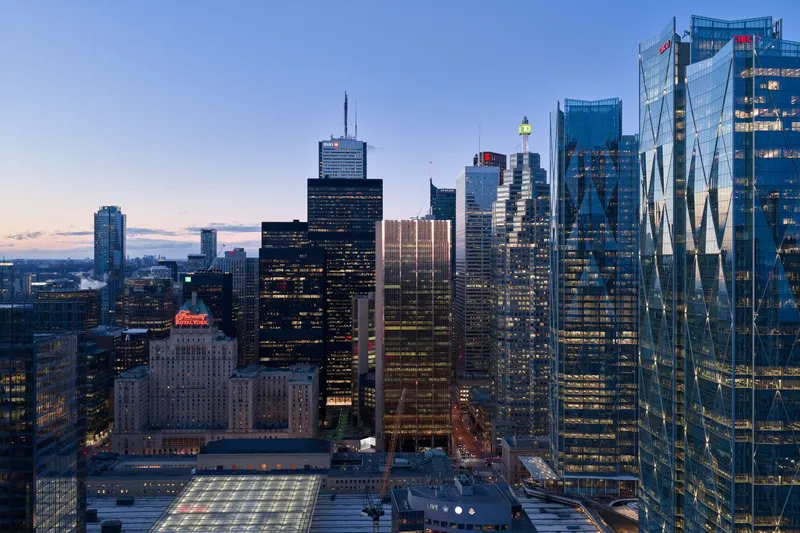 Downtown skyline view with illuminated glass towers and railway infrastructure below at sunset