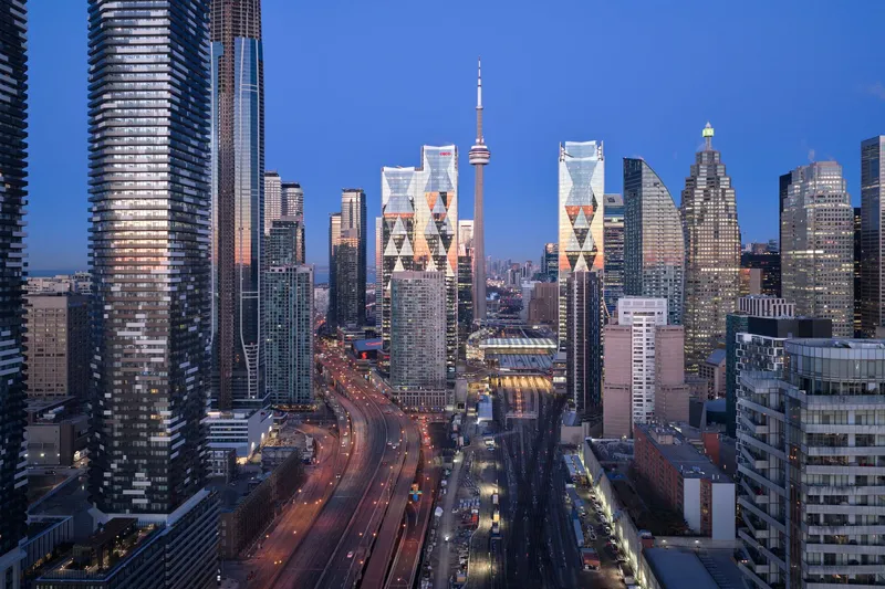 Wide cityscape showing the twin towers flanking a multi-lane highway with car light trails