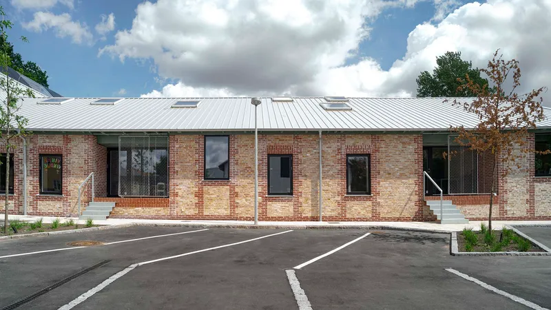 Street facade with mixed brick patterns and standing seam metal roof under a cloudy sky
