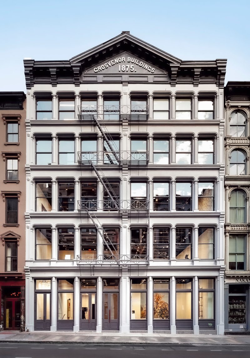 Five-story cast-iron facade with pediment and large glazed openings in late afternoon light