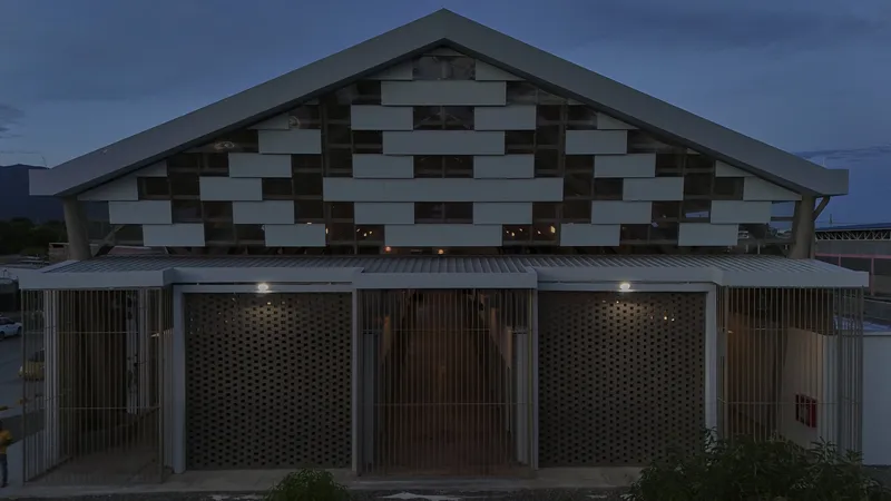 Gabled facade with chequered panel pattern above perforated timber screens at twilight