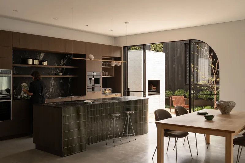 Kitchen and dining area with fluted island and arched opening to courtyard beyond