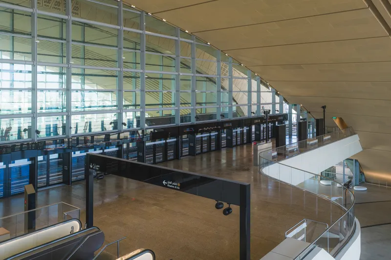 Interior concourse with curved ceiling, glass curtain wall, and spiral staircase descending to lower level