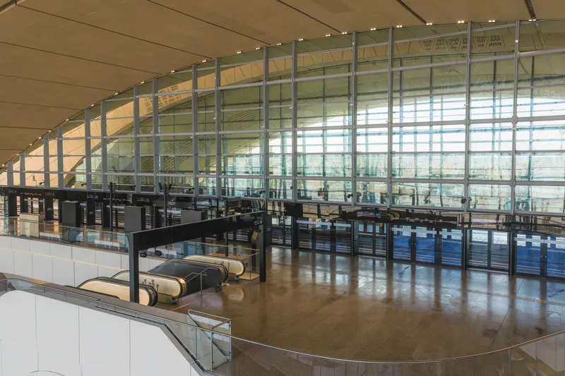 Upper level with curved glass balustrade overlooking rows of seating beneath a timber ceiling