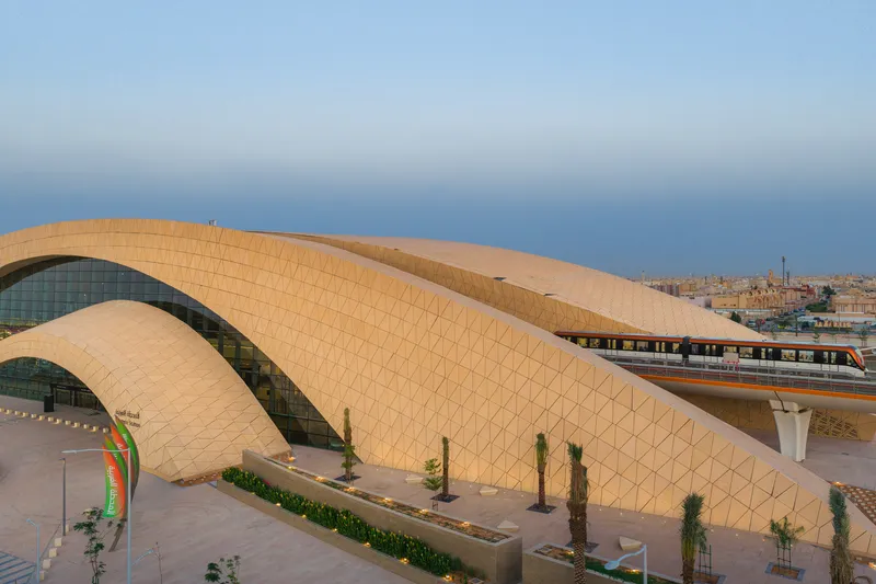Close view of the tiled shell roof with elevated train passing beneath against the urban skyline