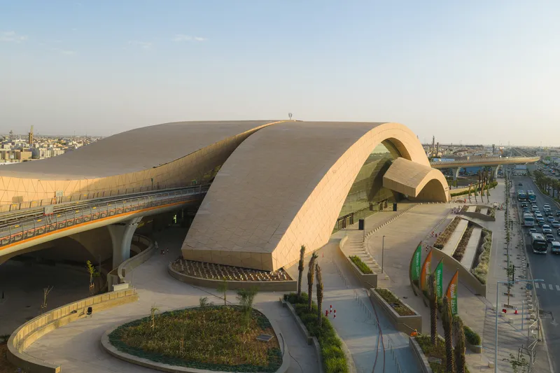 Long view of the arched roof forms with elevated rail line and landscaped plaza below