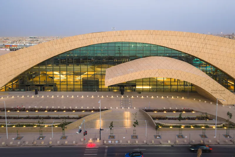 Elevated view of the arched facade with glass curtain wall at dusk above the access road