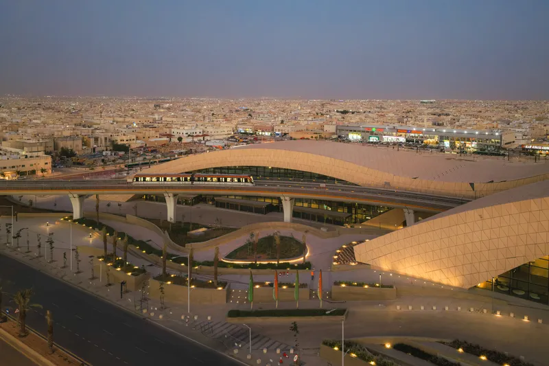Aerial view of the curved roof spanning over highway infrastructure and planted courtyards at twilight