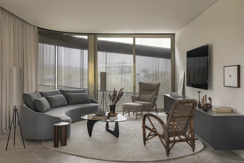 Living room with curved sofa and floor-to-ceiling windows framed by vertical metal screens