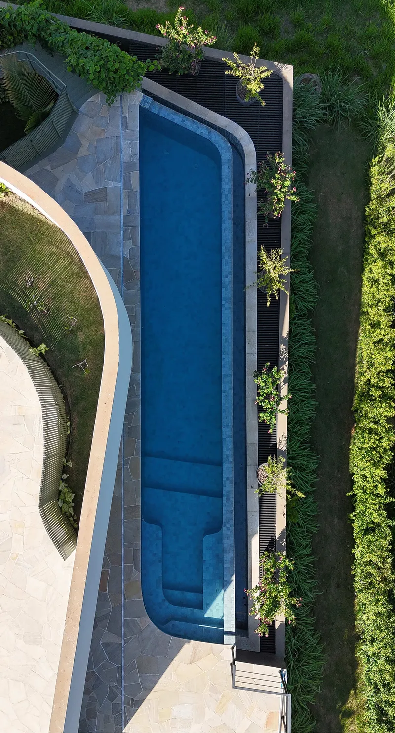 Aerial view of a curved lap pool with stone deck and flanking lawns