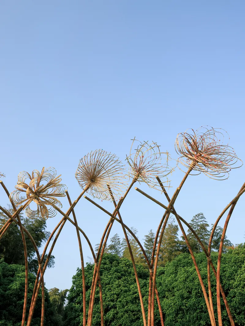 Upward view of the bamboo flower forms with radiating woven petals silhouetted against a blue sky