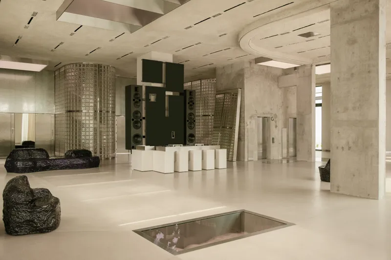 Lobby space with exposed concrete columns, curved ceiling cutout and recessed floor opening with glass