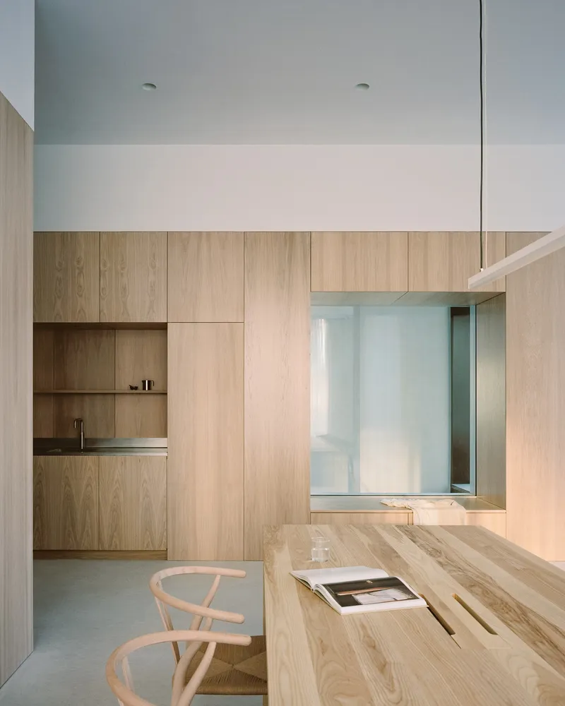 Kitchen nook with timber cabinetry and glimpse into courtyard through internal glazing