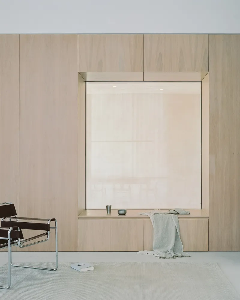 Timber-framed window alcove with built-in bench and sheer white roller shade in pale interior