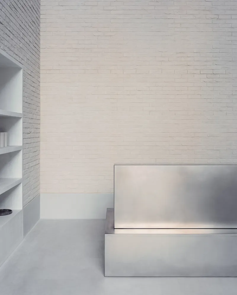 Detail of stainless steel stair treads with integrated lighting against a white painted brick wall