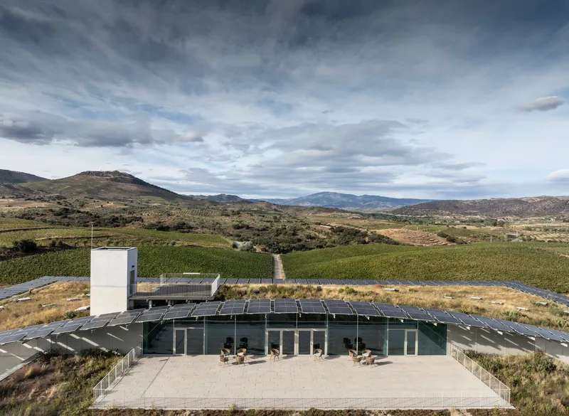 Elevated view of winery terrace framed by solar panels and vineyards under cloudy sky