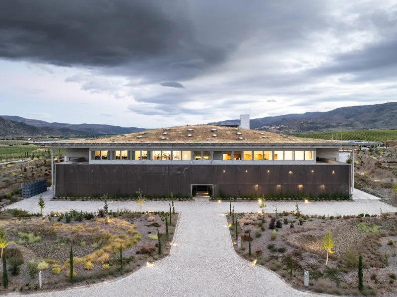 Long view of the planted green roof with a central chimney under stormy evening skies