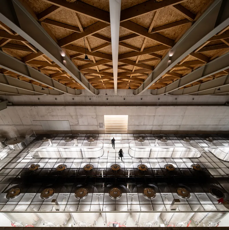 Interior view of the production floor with exposed concrete beams and coffered cork ceiling panels