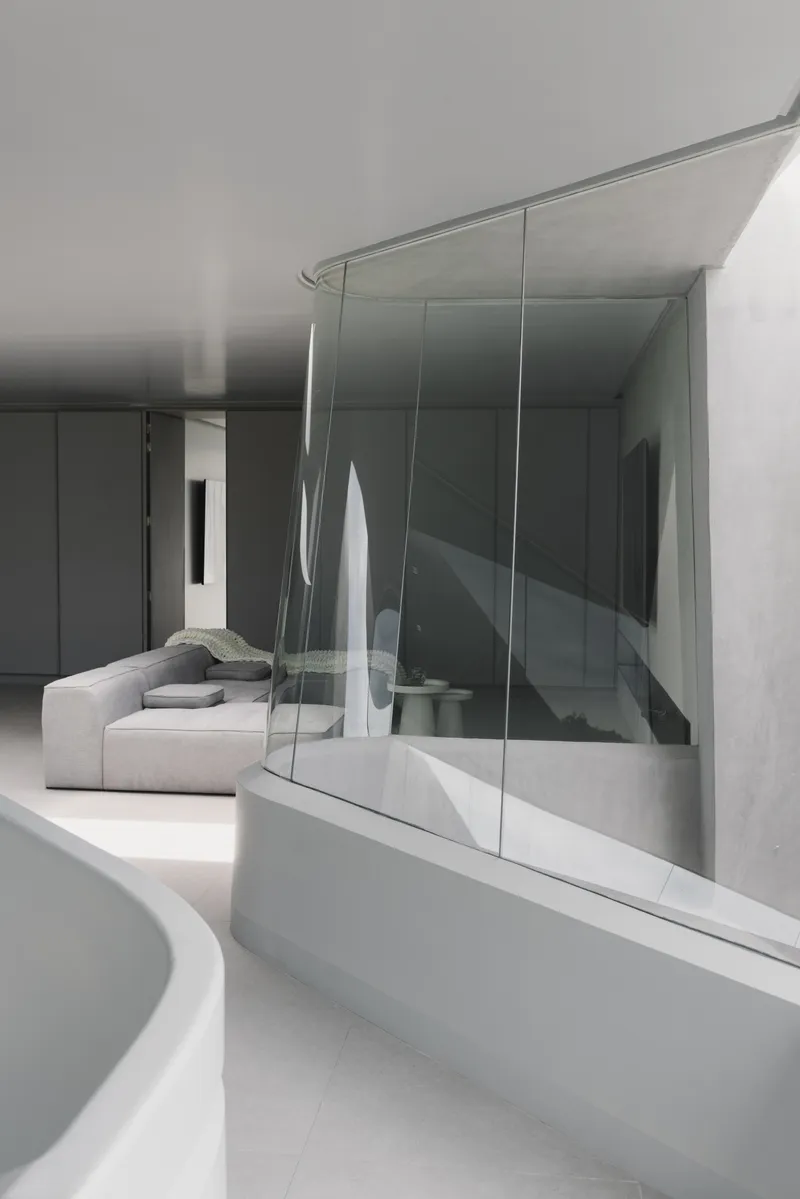 Glass-edged void looking down onto the sculptural white staircase from the upper level