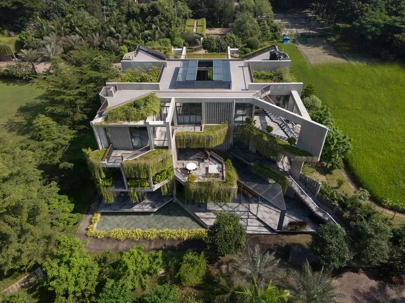 Aerial view of the multi-level residence with planted terraces and green roofs surrounded by trees and lawn
