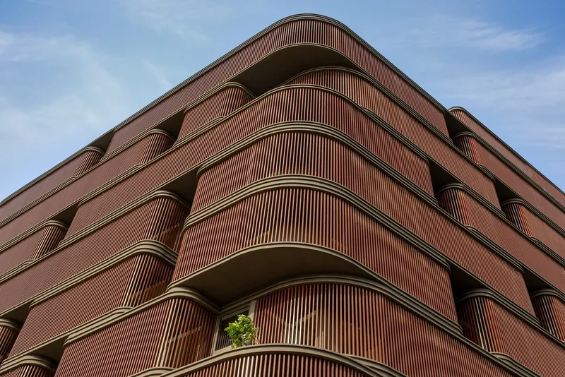 Corner view of the layered balconies with ribbed timber screens and potted greenery