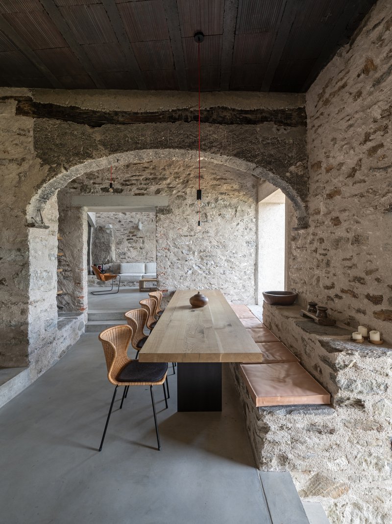 Dining area beneath stone arches with timber ceiling and view through to adjacent rooms