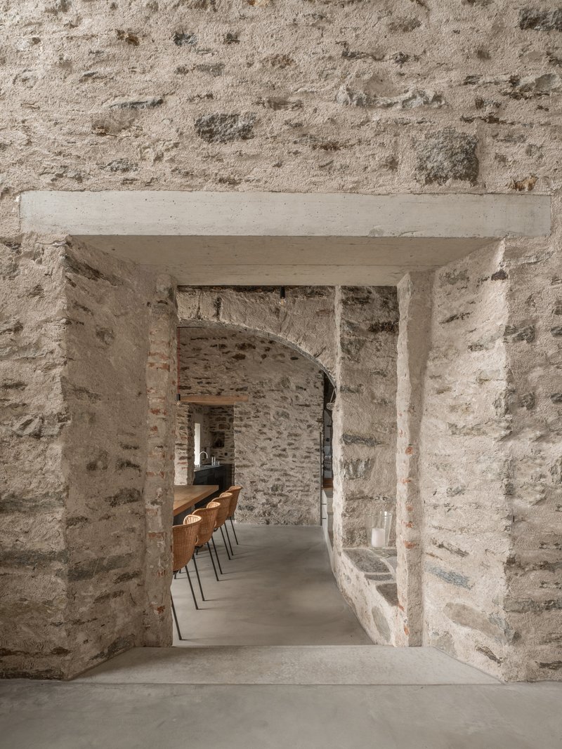 Stone archway framing a sequence of openings with dining chairs visible beyond