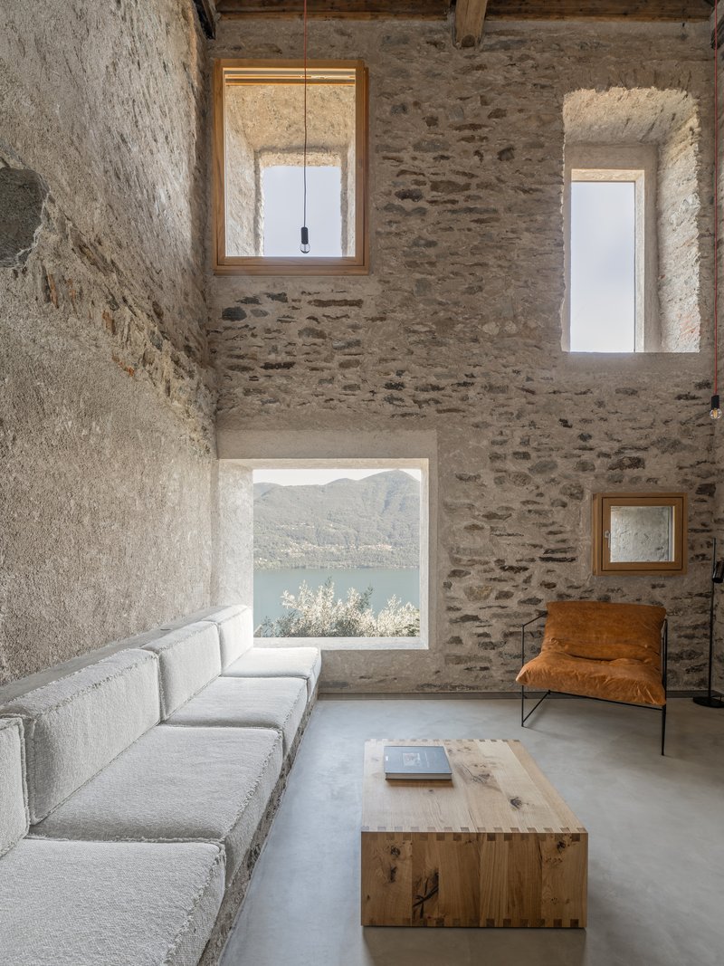 Sitting area with stone walls and window framing a lake view under diffused daylight