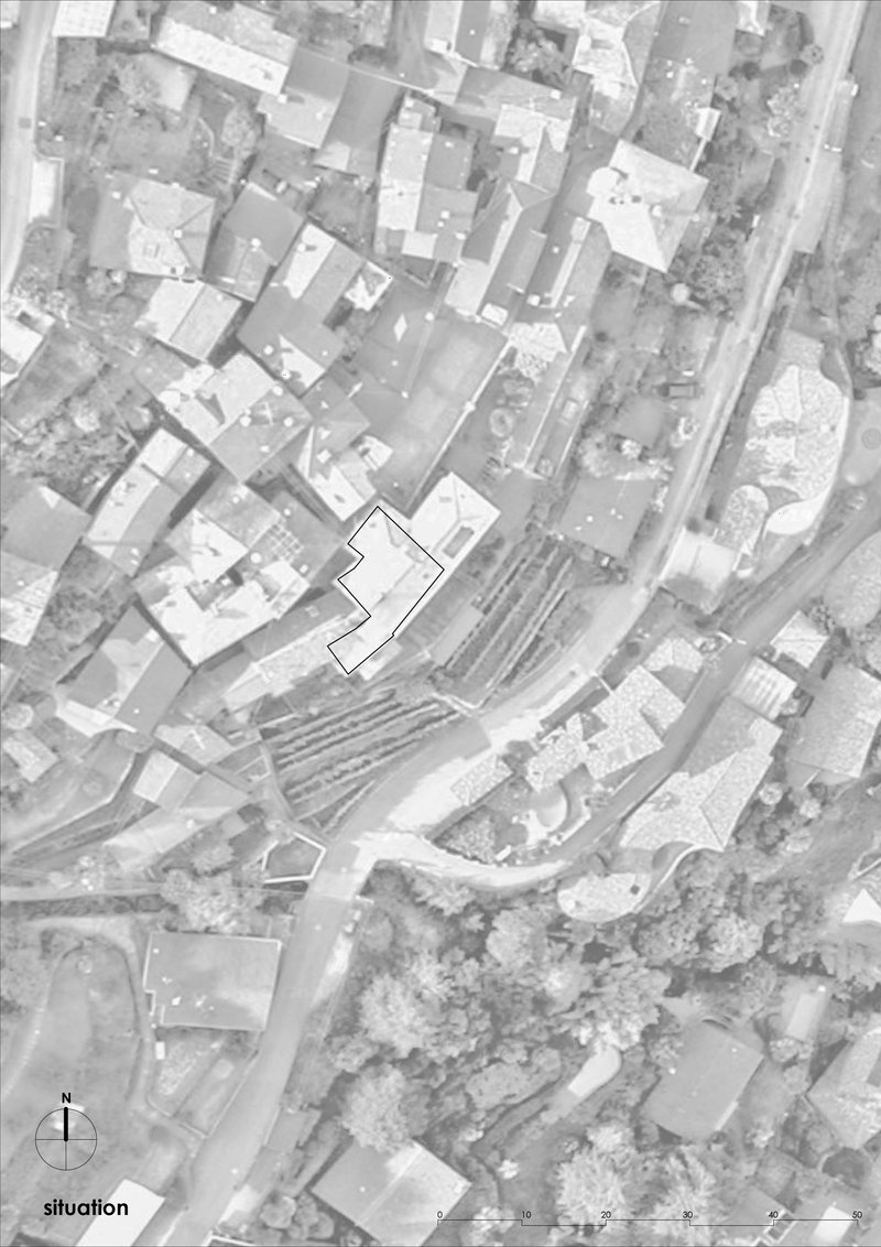 Site plan drawing showing a building footprint outlined among residential structures and dense tree cover