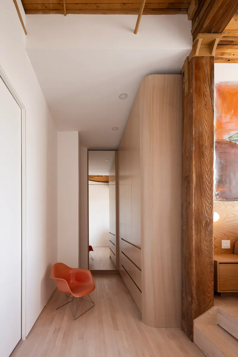 Narrow corridor with exposed timber beams above and curved built-in cabinetry along one wall